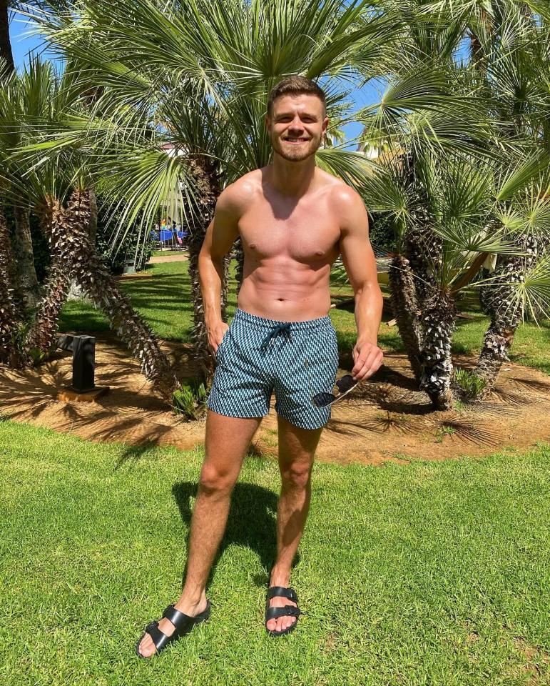 Tom McDonnell, a TOWIE star, standing outdoors in swim shorts and sandals.