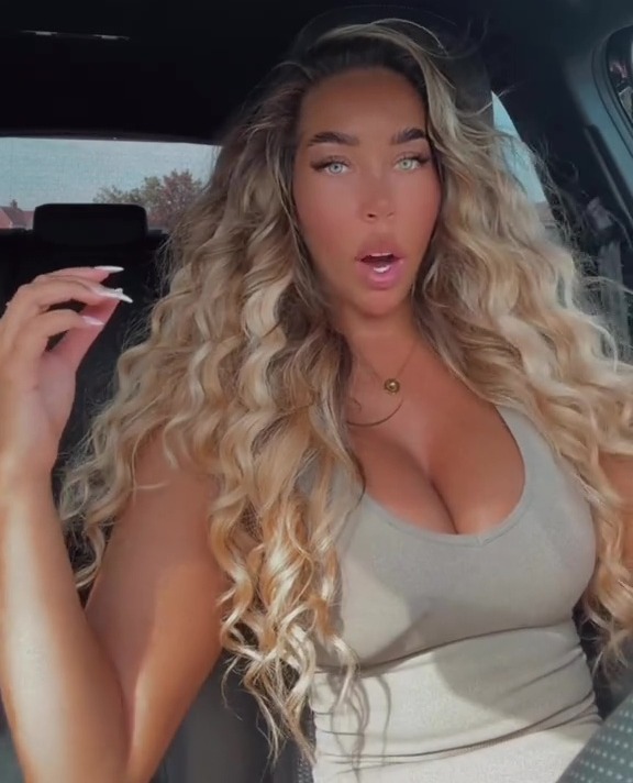 A woman in a car with curly blonde hair and bright blue eyes, with text overlay saying "Just the people in the UK being bad vibes once again."