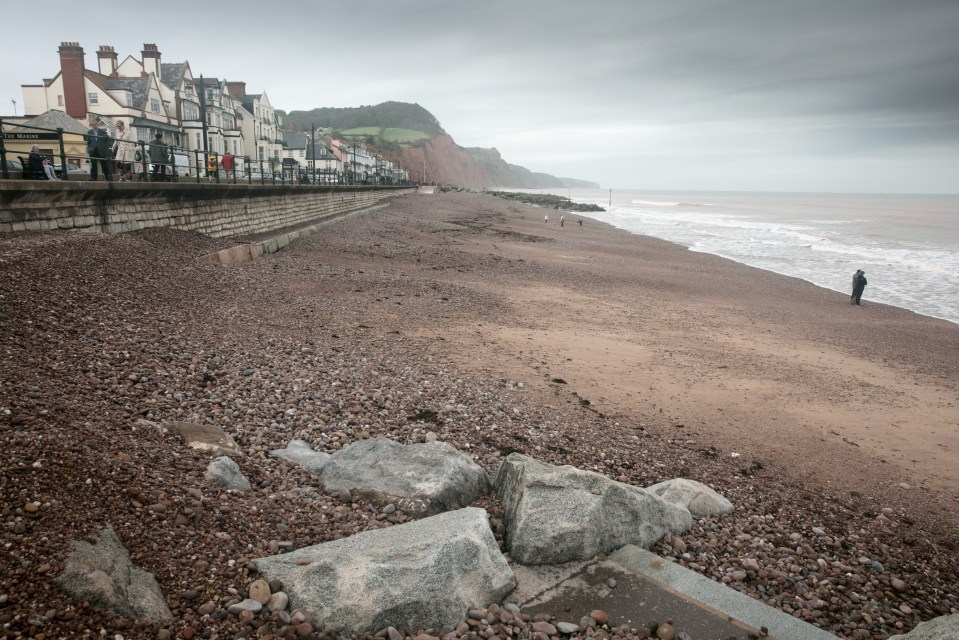 People walk along the promenade and beach in Sidmouth, Devon, where jellyfish have been washed ashore by ex-hurricane Ophelia.