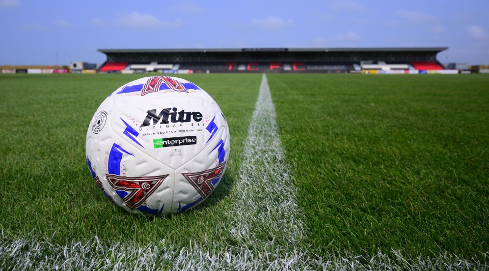 Soccer ball on field with stadium in background.