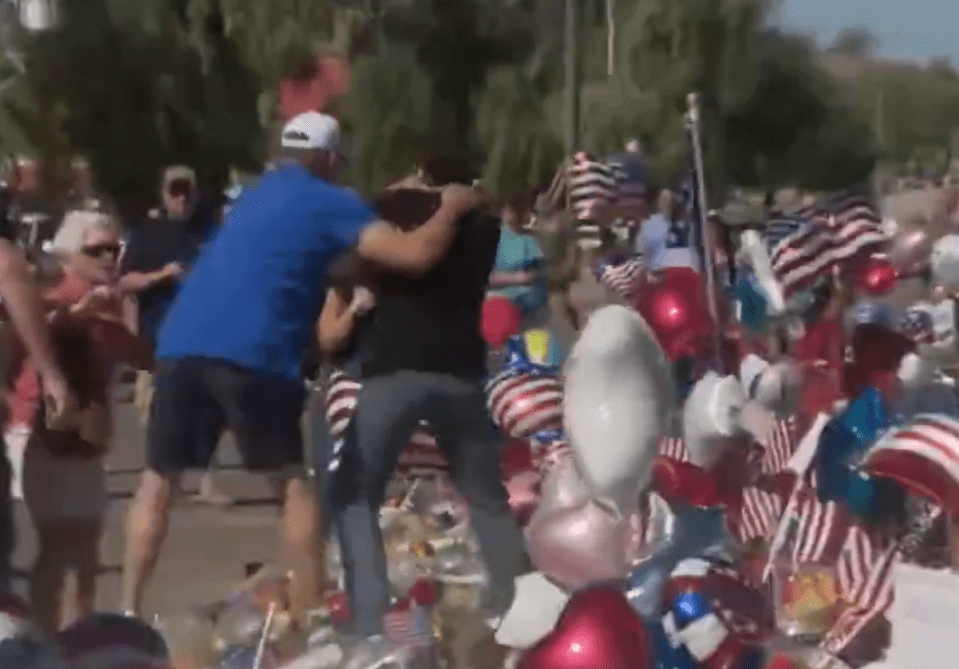 A man grabbing a woman amidst a crowd and patriotic decorations.