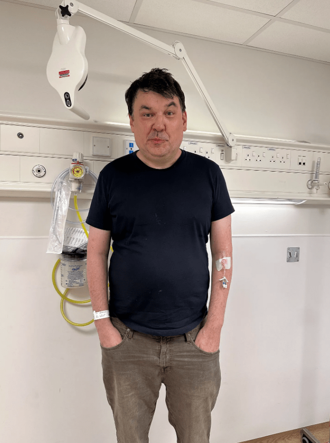 Graham Linehan in a hospital room with an IV in his arm.