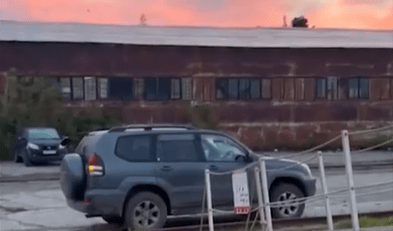 Gray SUV parked in front of a rusty building.