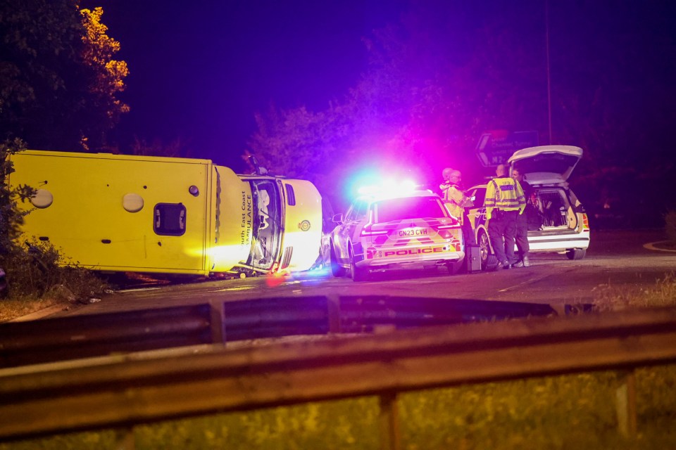 Overturned ambulance at night with police on scene.