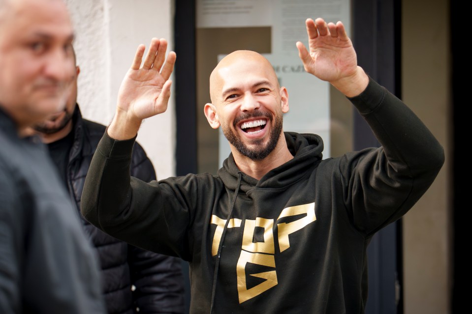 Andrew Tate laughing while checking in at a police station.