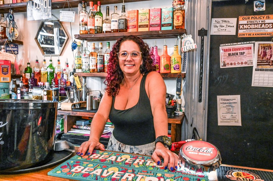 A barmaid stands behind a bar at a pub.