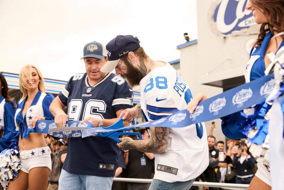 Two football players cutting a ribbon at a Raising Cane's opening.
