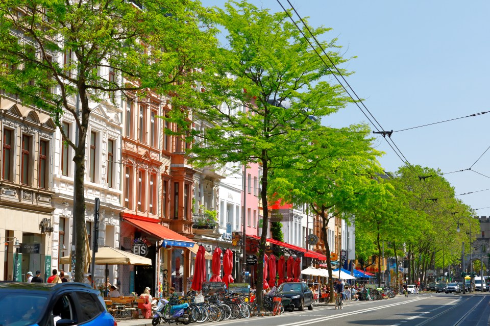 Aachener Straße in Cologne's Belgian Quarter, showing 19th-century buildings with outdoor cafes.
