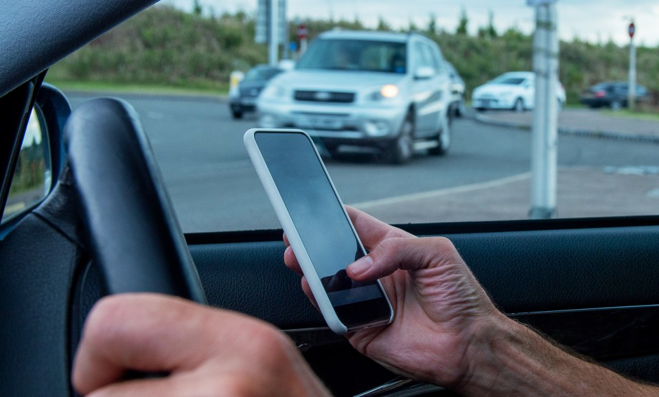 Person driving a car while using a smartphone.