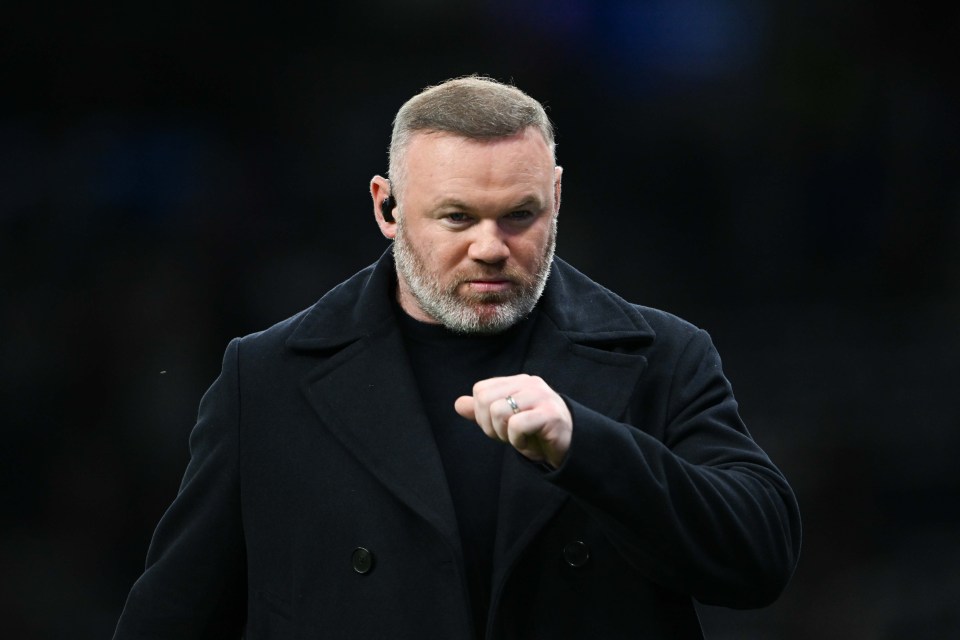 Wayne Rooney speaking, wearing a dark coat and earpiece.