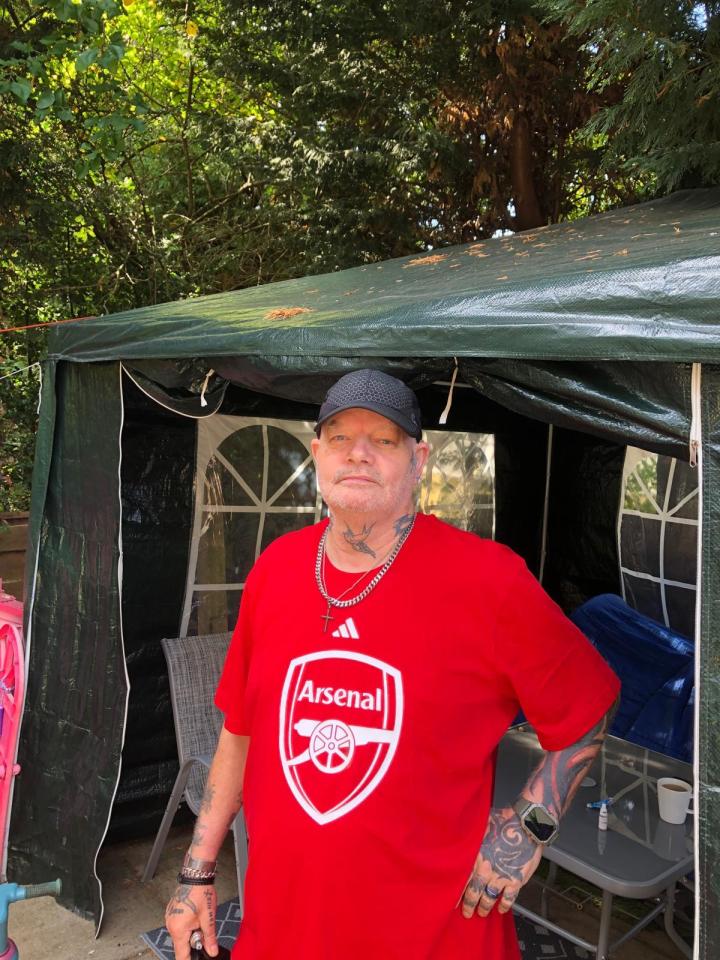 Man wearing an Arsenal t-shirt under a tent.