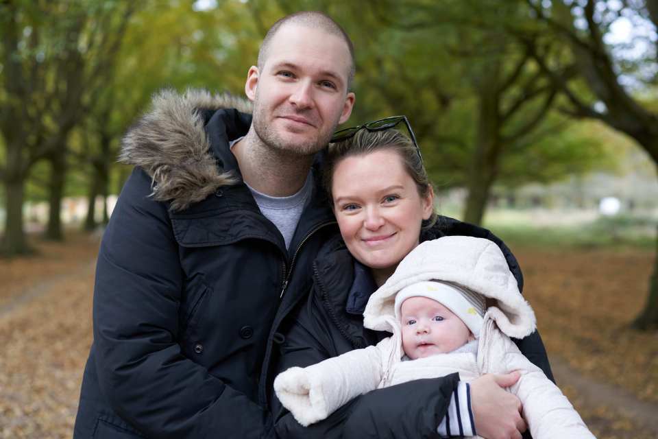 Rosie Bridge held by her mother, with her father standing next to them.