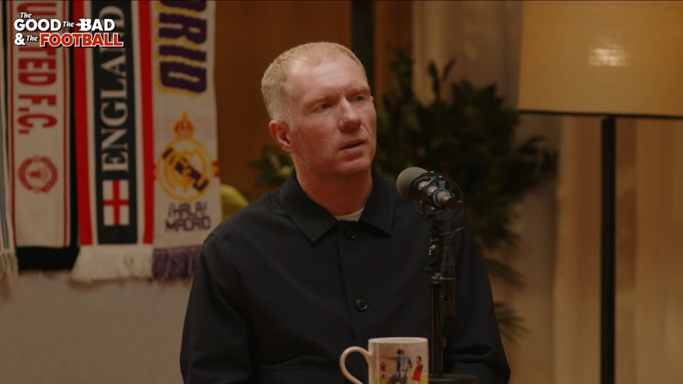 Paul Scholes sitting at a table with a microphone in front of him, with "The Good, The Bad & The Football" logo in the top left corner, and several football scarves hanging in the background.