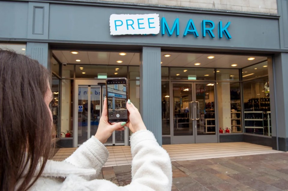 A person taking a photo of the "Pree Mark" store sign with their phone.