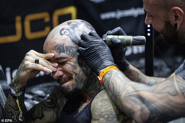 A man appears to get another tattoo behind his year at this year's Big London Tattoo Show