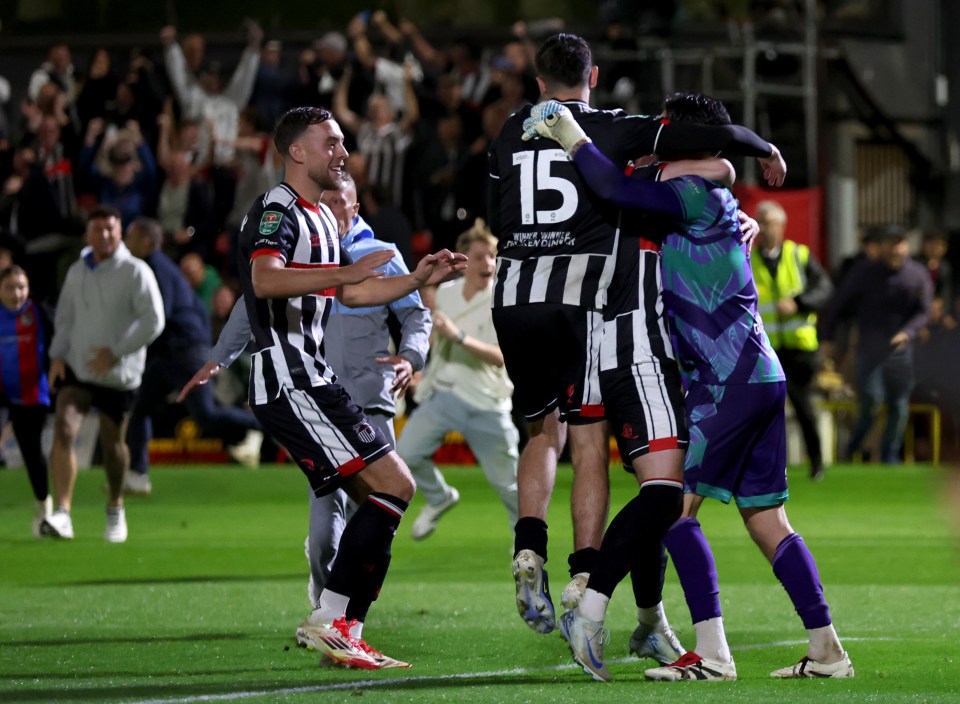 Grimsby Town's goalkeeper, Christy Pym (right), is congratulated by teammates after a victory in a penalty shoot-out.