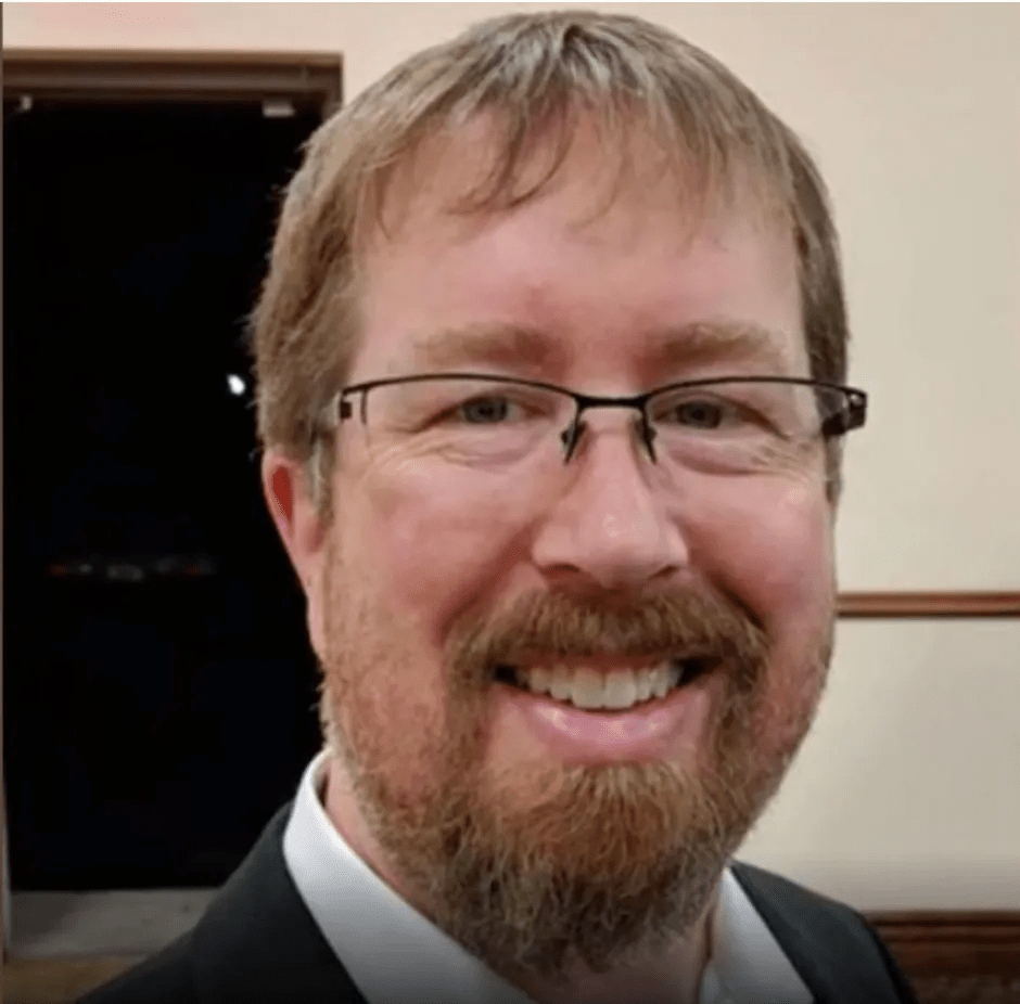 Headshot of a smiling man with glasses and a beard.