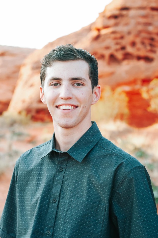 Portrait of a smiling young man wearing a dark green button-down shirt.