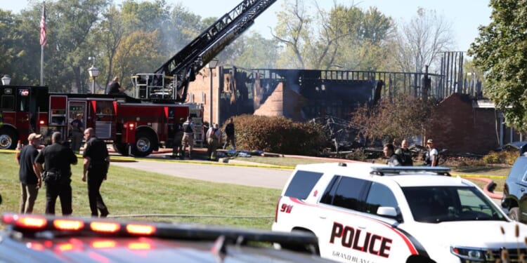 Fire and law enforcement officers stand outside the Church of Jesus Christ of Latter-day Saints in Grand Blanc Township, Michigan, following a shooting and fire on Sunday.
