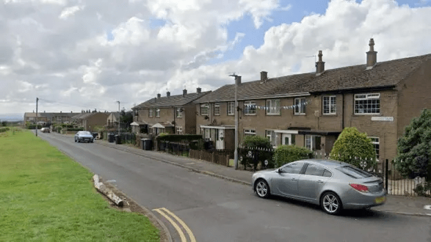 Residential street with row houses and a car.