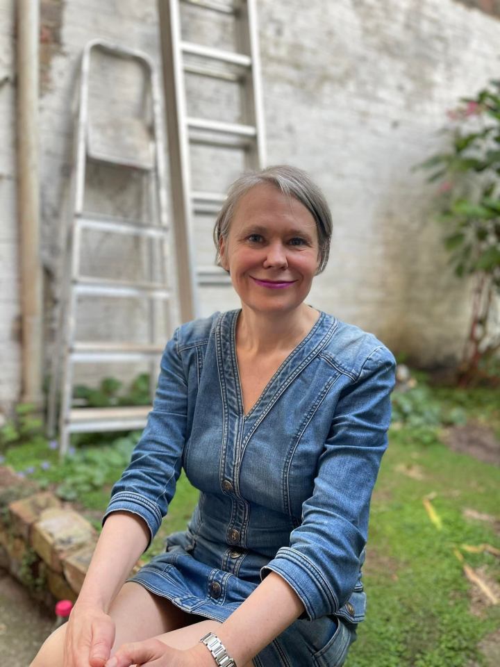 Woman in denim dress sitting outdoors.