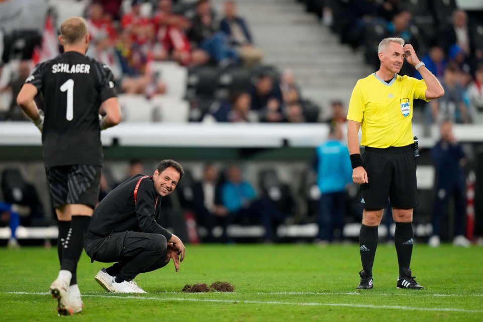 A groundskeeper repairs a section of a soccer field during a match.