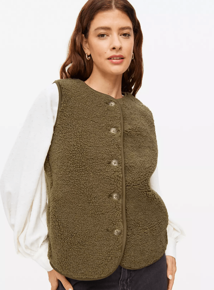 Woman wearing a green fleece vest over a white long-sleeved shirt.