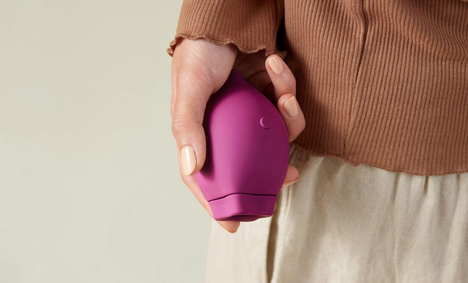 A person's hand with nude nail polish holding a purple Poet device.