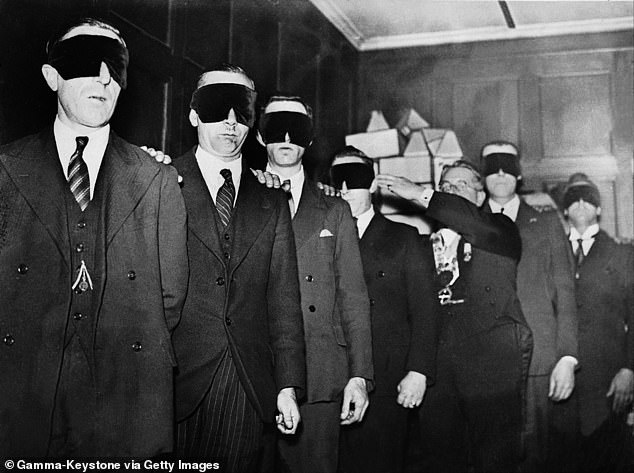 Future members of an English freemasonry lodge being guided with their eyes covered during their initiation in around 1933