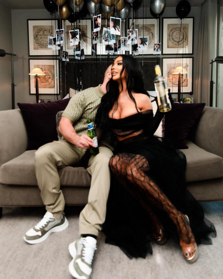 Chelsee Healey posing with her partner on a couch, both holding drinks.