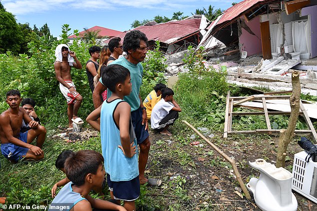 People gather to inspect a collapsed building after the earthquake killed dozens of people