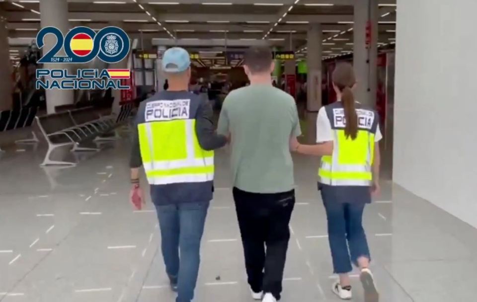 Tyler Robert Buchanan being escorted by two Policia Nacional officers in an airport.