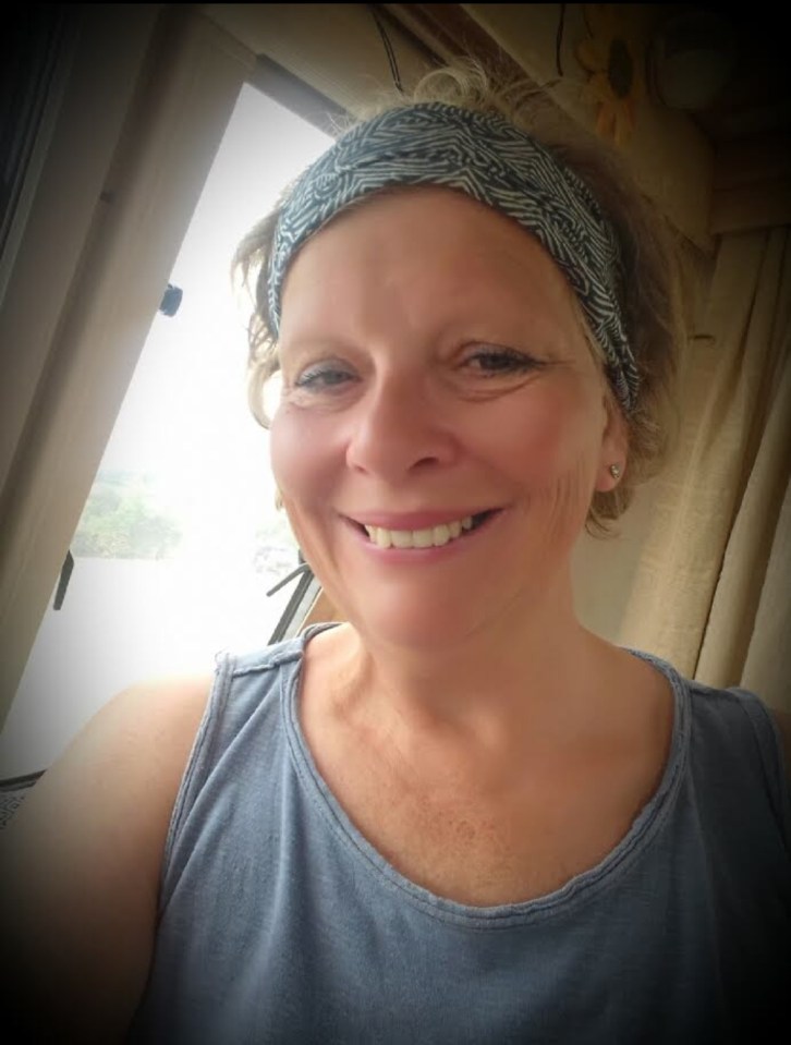 Smiling woman with a patterned headband in a light-colored top.