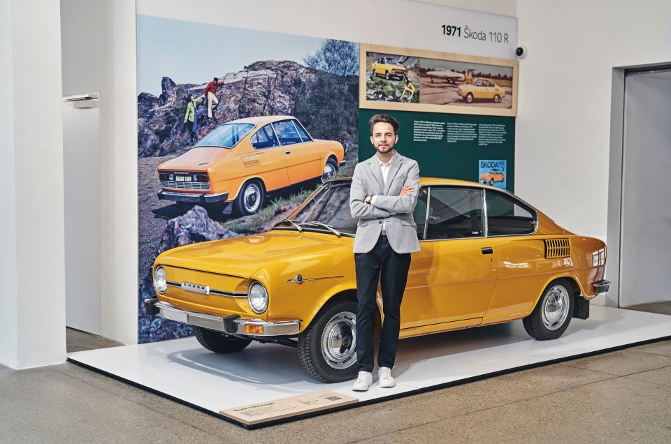 Richard Švec, designer and member of the digital modeling team at Škoda Design, stands next to a yellow 1971 Škoda 110 R.