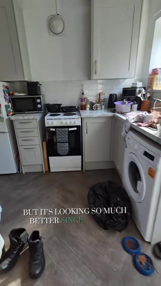 A cluttered kitchen with white cupboards and appliances, including a washing machine and oven.