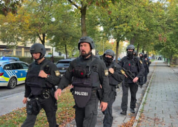Police officers walk along a footpath after a fire in a detached house in Munich, Germany, on Wednesday.