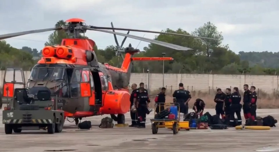 Military Emergency Unit members and a helicopter in Ibiza for flood relief efforts.