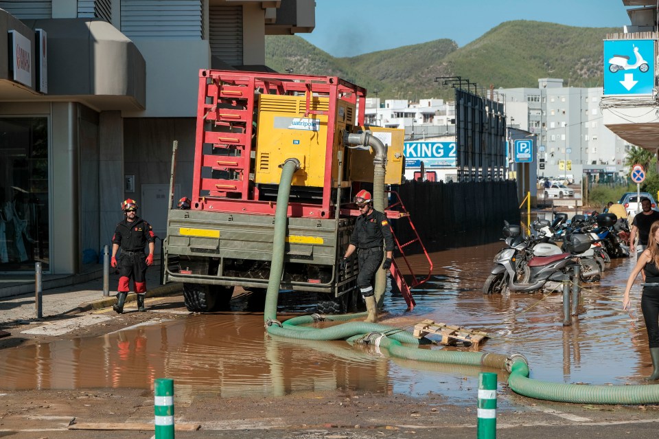 Firefighters use a large pump to remove floodwater from a street in Ibiza, Spain.