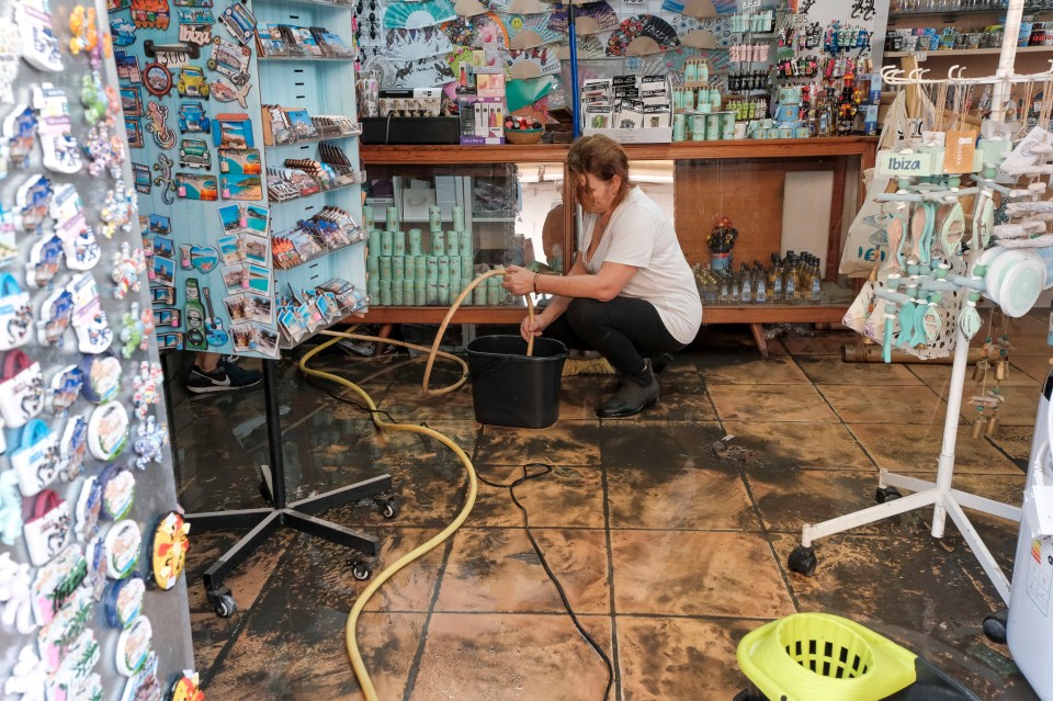 A person cleaning a souvenir shop damaged by floods in Ibiza, Spain.
