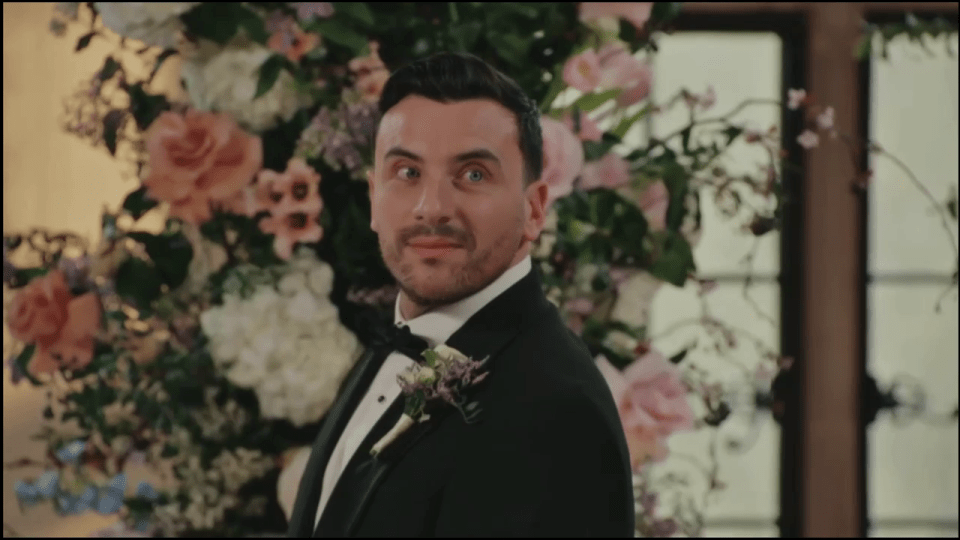 Groom looking left with a smirk at the altar.
