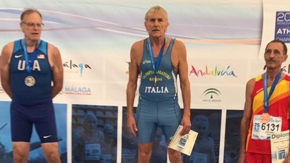 Lamberto Boranga standing on the medal podium with two other athletes.