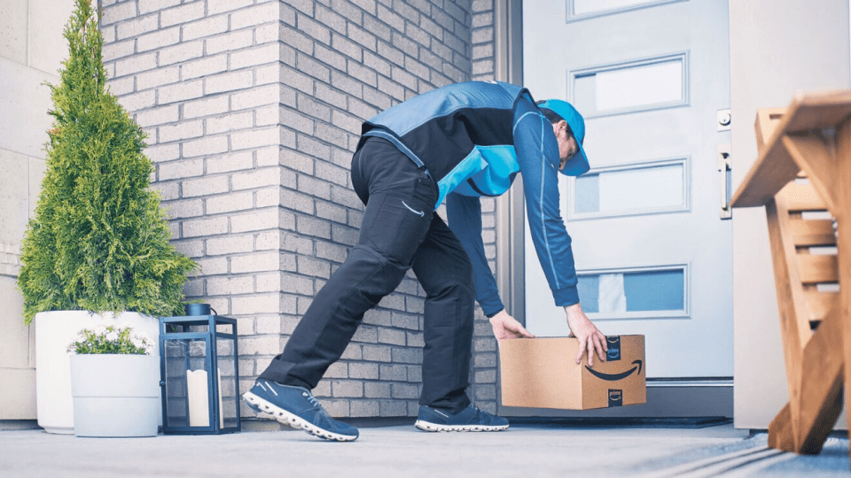 An Amazon delivery person placing a package on a doorstep.