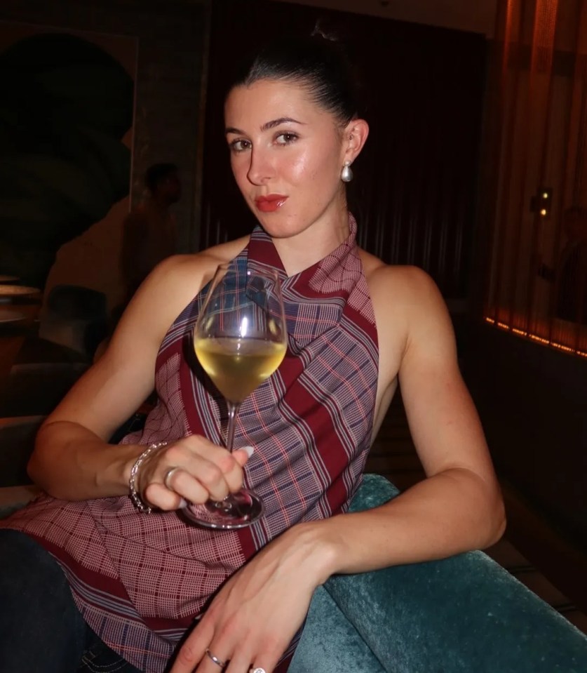 Athlete Amy Hunt holding a glass of white wine while sitting.