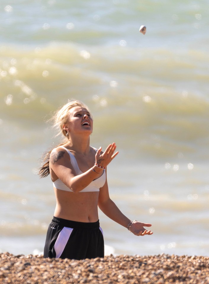 JoJo Siwa throwing a stone into the sea on Brighton Beach.