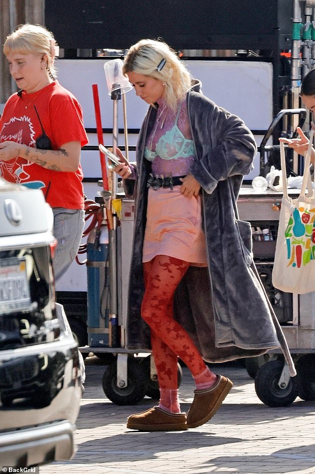 Wiig, 52, was equally eye-catching in costume, sporting red lace tights, a pink mini-skirt, a turquoise bra layered over a lilac top and a velvet bathrobe as the pair filmed outside their trailers