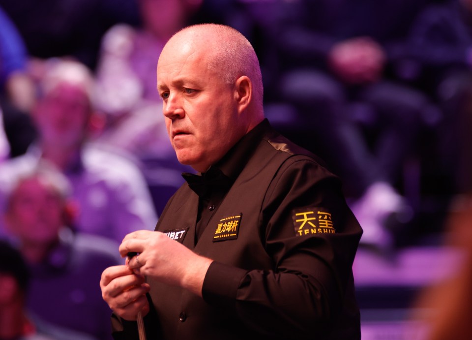 John Higgins of Scotland chalks his snooker cue.