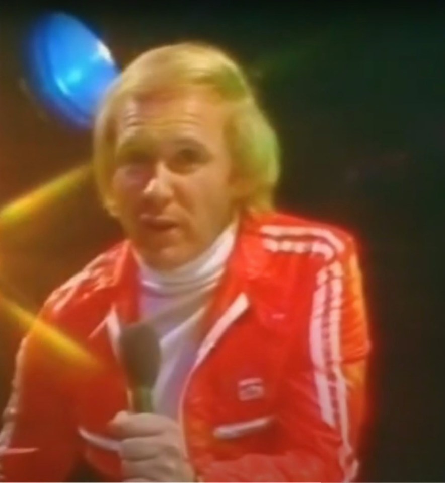 a man in a red adidas jacket is holding a microphone