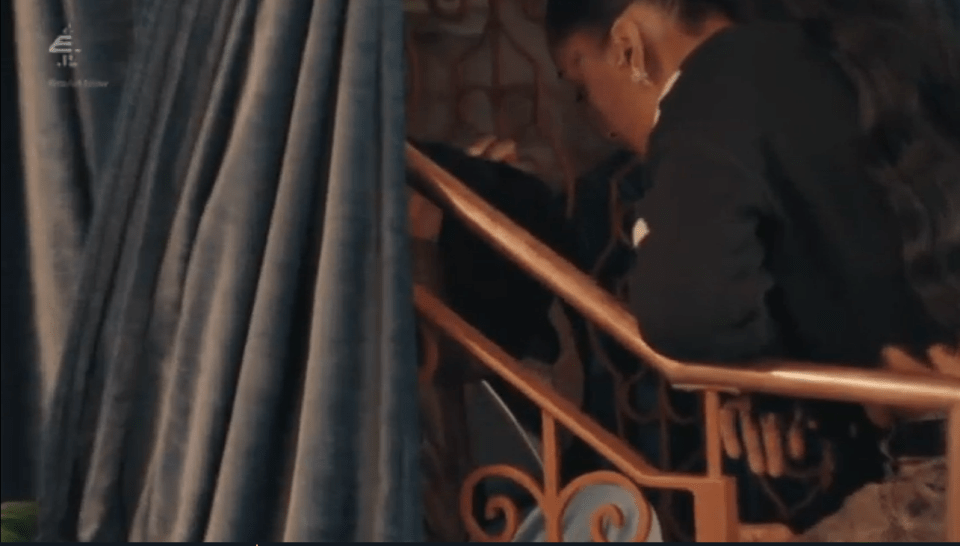 A person in a black top goes up the stairs next to a blue curtain.