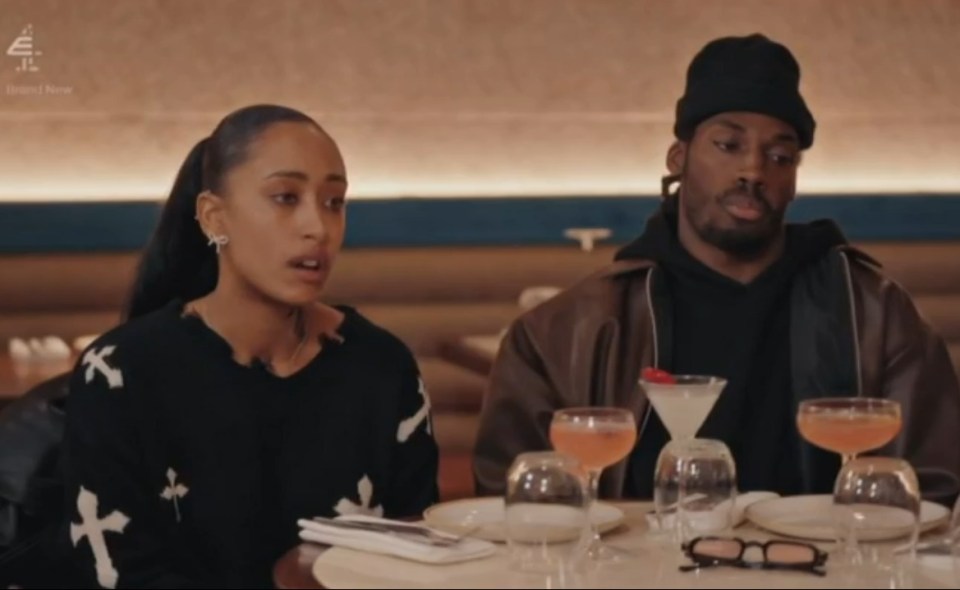 Two people, a man and a woman, seated at a restaurant table with drinks.