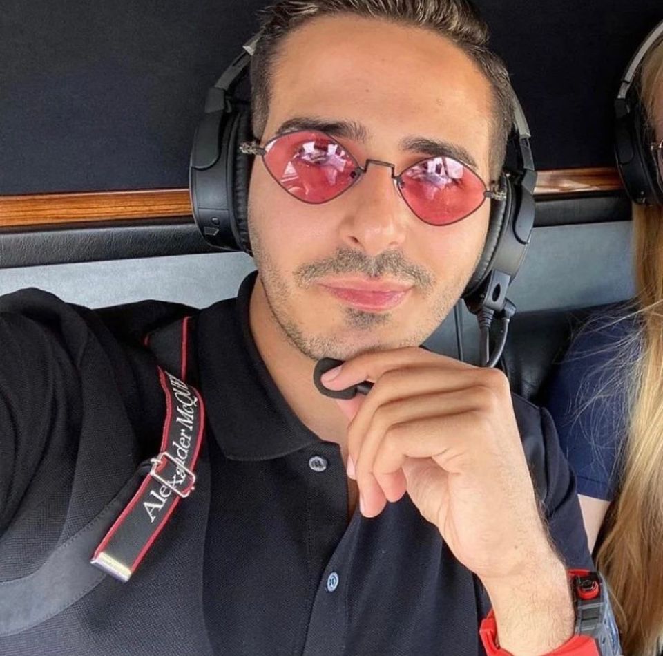 Simon Leviev in a black polo, red sunglasses, and headphones with a microphone.